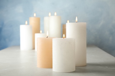 Burning candles on table against color background