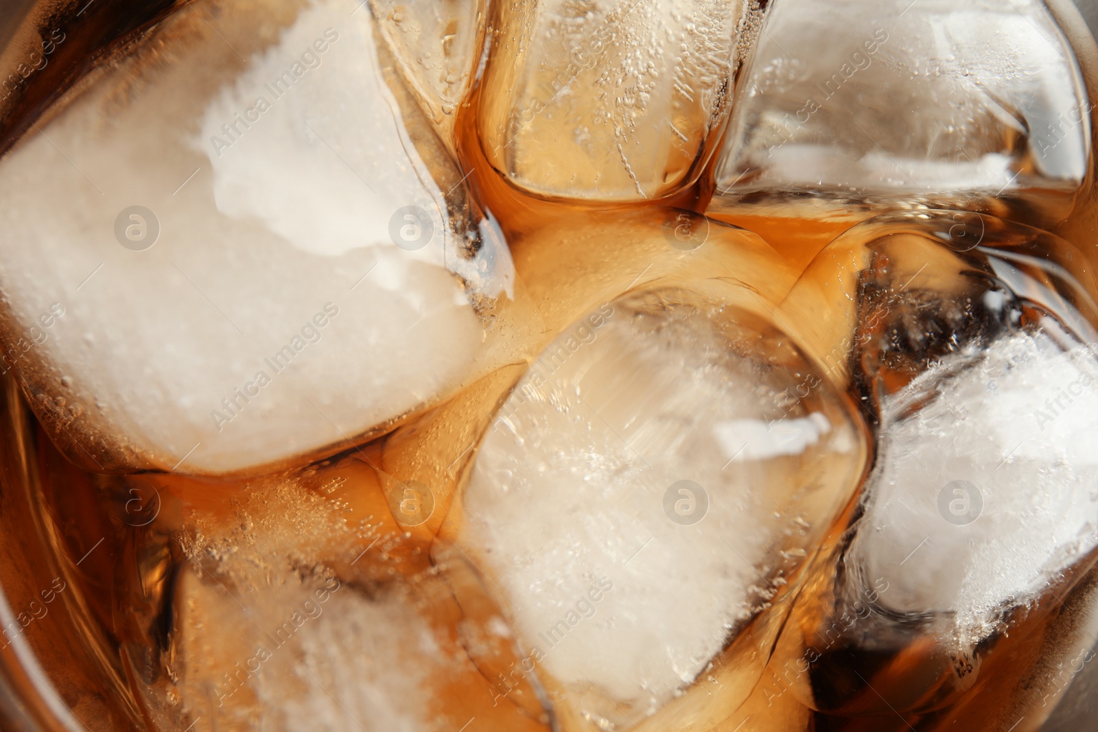 Photo of Closeup view of tasty refreshing cola with ice cubes as background