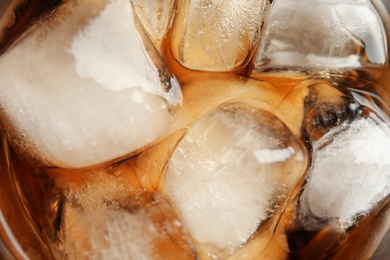 Closeup view of tasty refreshing cola with ice cubes as background