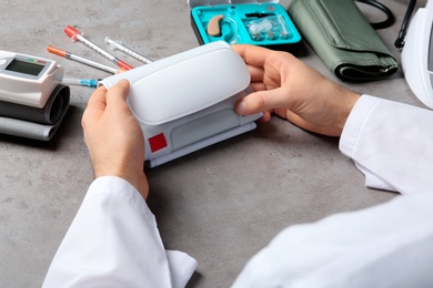 Photo of Doctor with digital pressure meter and different medical objects at table, closeup