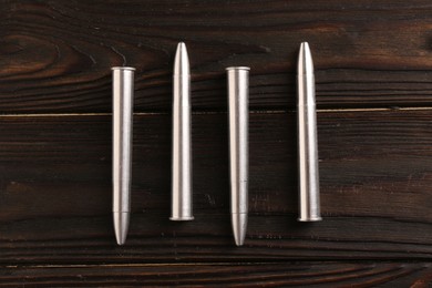 Metal bullets on dark wooden table, flat lay