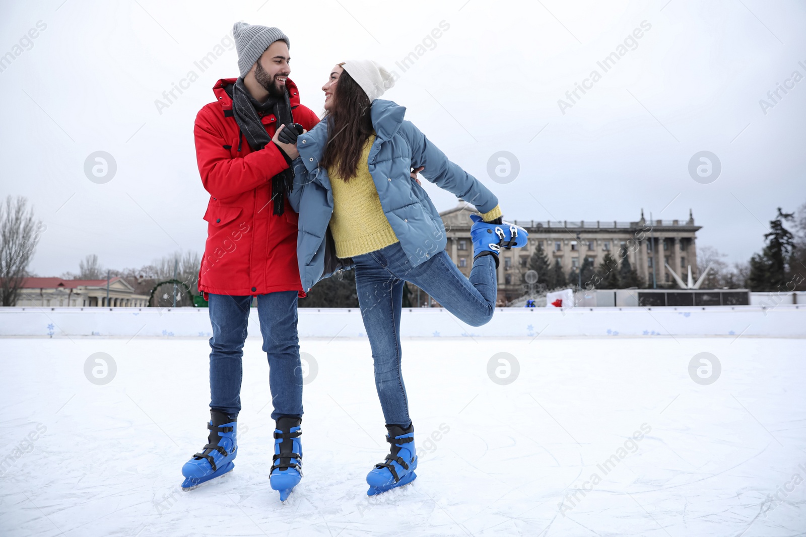 Image of Happy couple skating along ice rink outdoors. Space for text