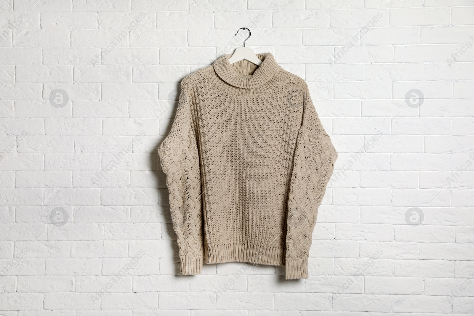 Photo of Hanger with stylish sweater on brick wall