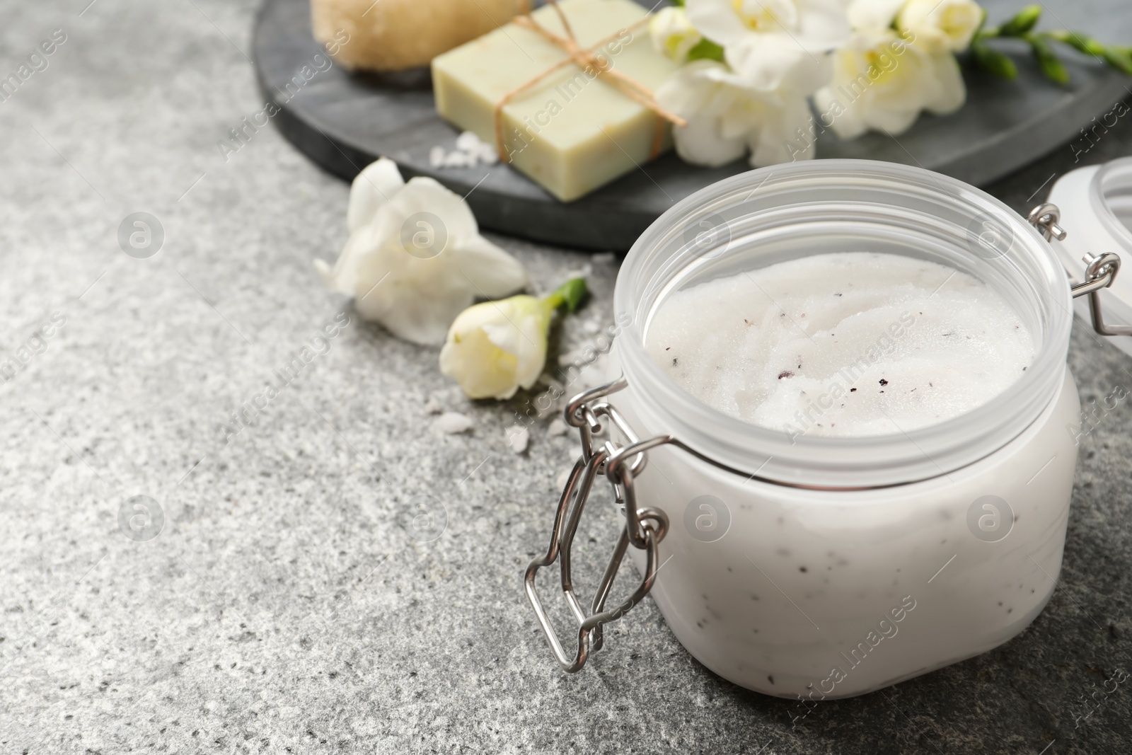 Photo of Body scrub in glass jar on grey table, space for text