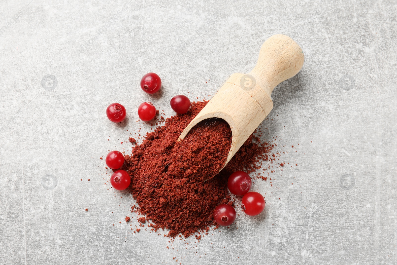 Photo of Pile of cranberry powder, scoop and fresh berries on light grey table, top view