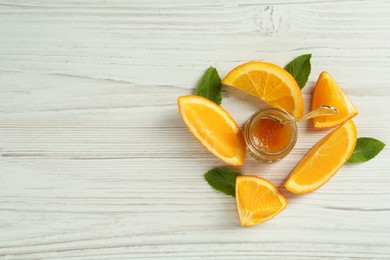 Photo of Jar of sweet orange jam and mint on white wooden table, flat lay. Space for text