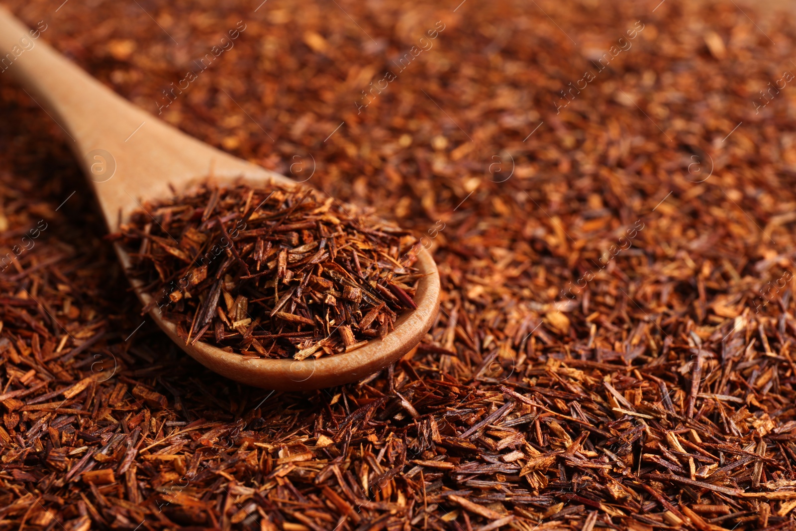 Photo of Heap of dry rooibos tea leaves with wooden spoon, closeup. Space for text