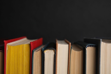 Photo of Stack of hardcover books on black background, closeup. Space for text