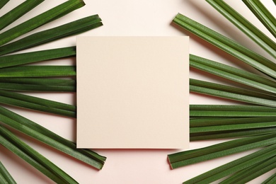 Photo of Creative composition with tropical leaves and card on light background, top view