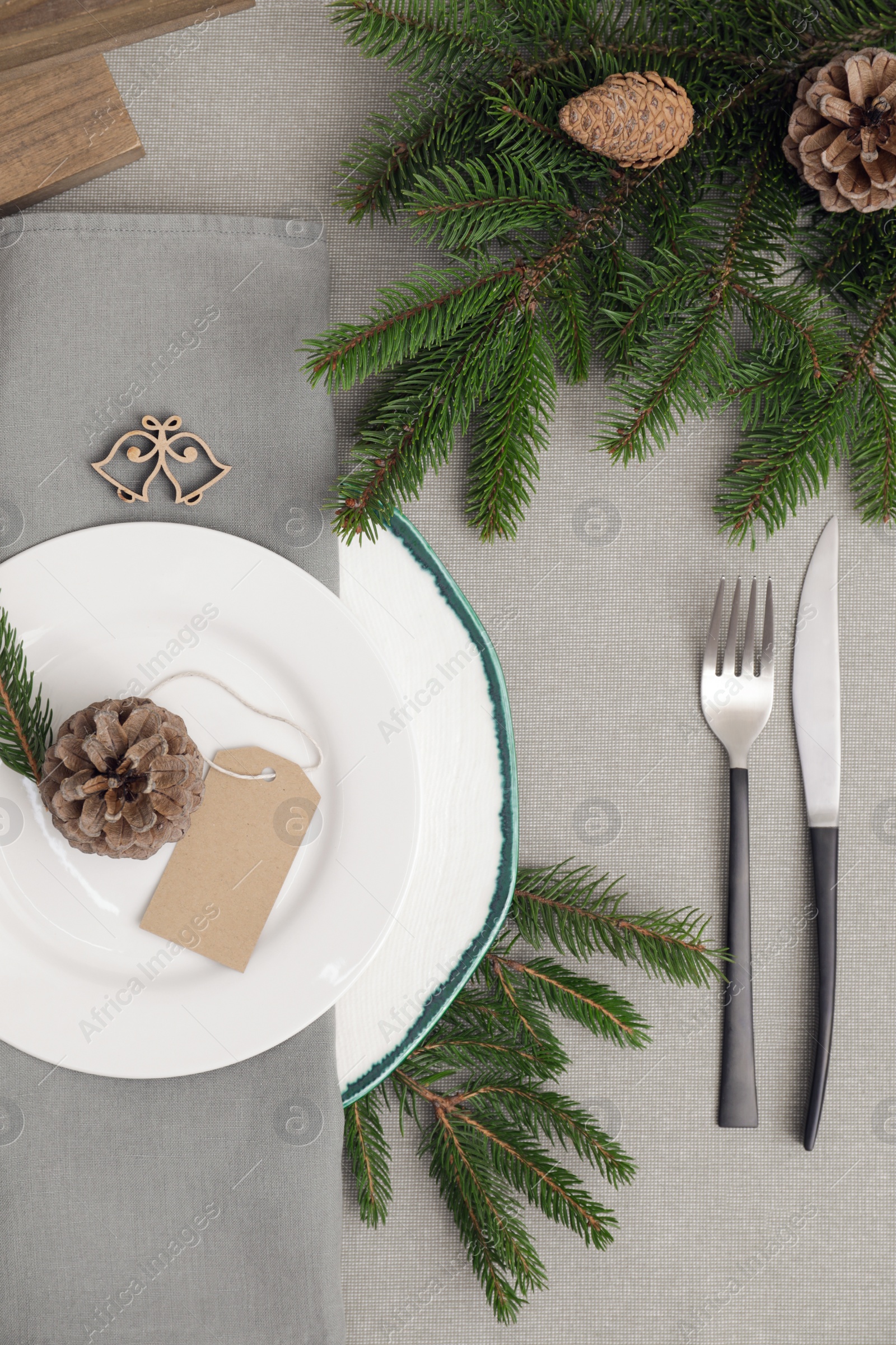 Photo of Festive place setting with beautiful dishware, cutlery and cone for Christmas dinner on grey table, flat lay