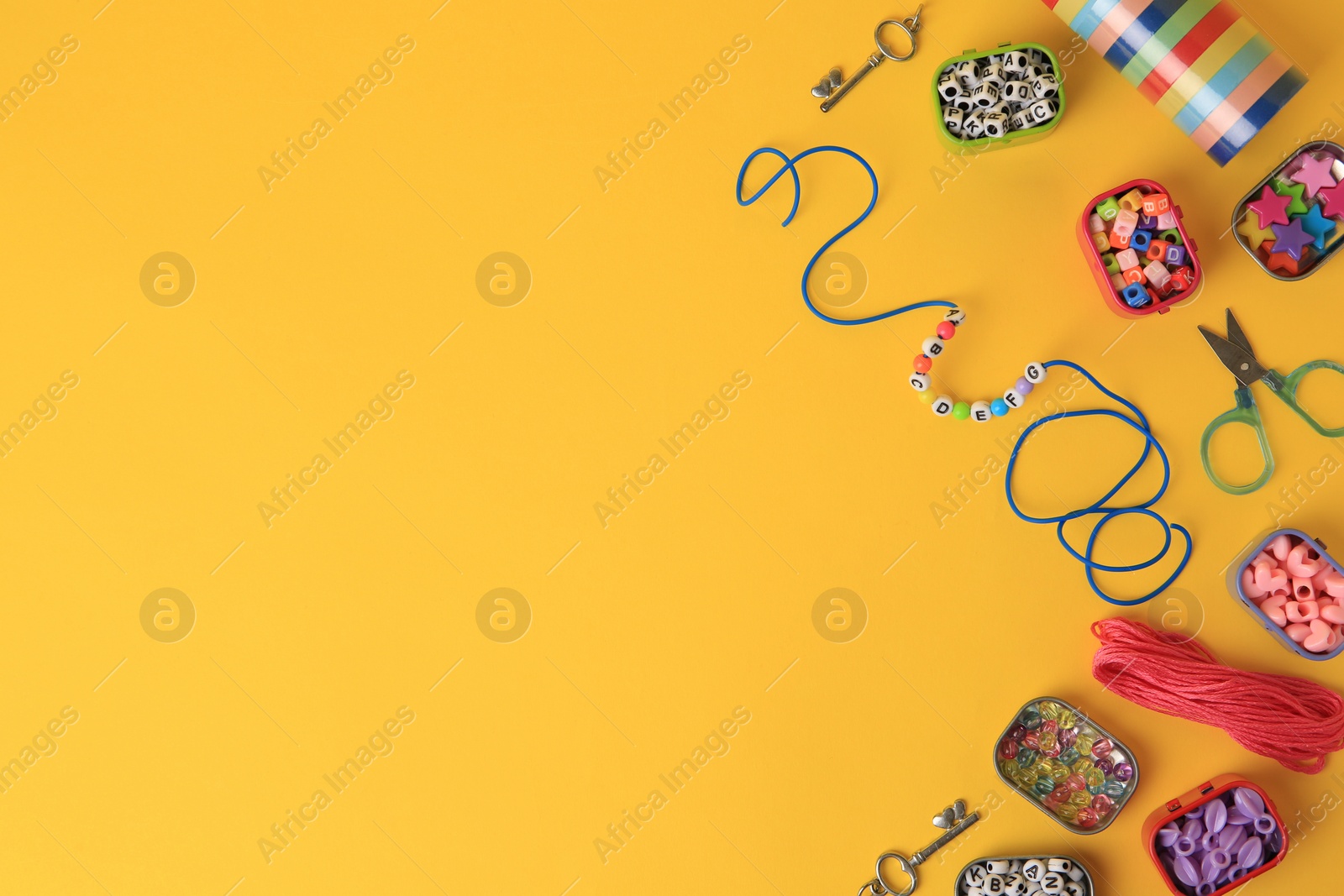 Photo of Kid`s handmade jewelry kit. Colorful beads, bracelet and different supplies on orange background, flat lay. Space for text