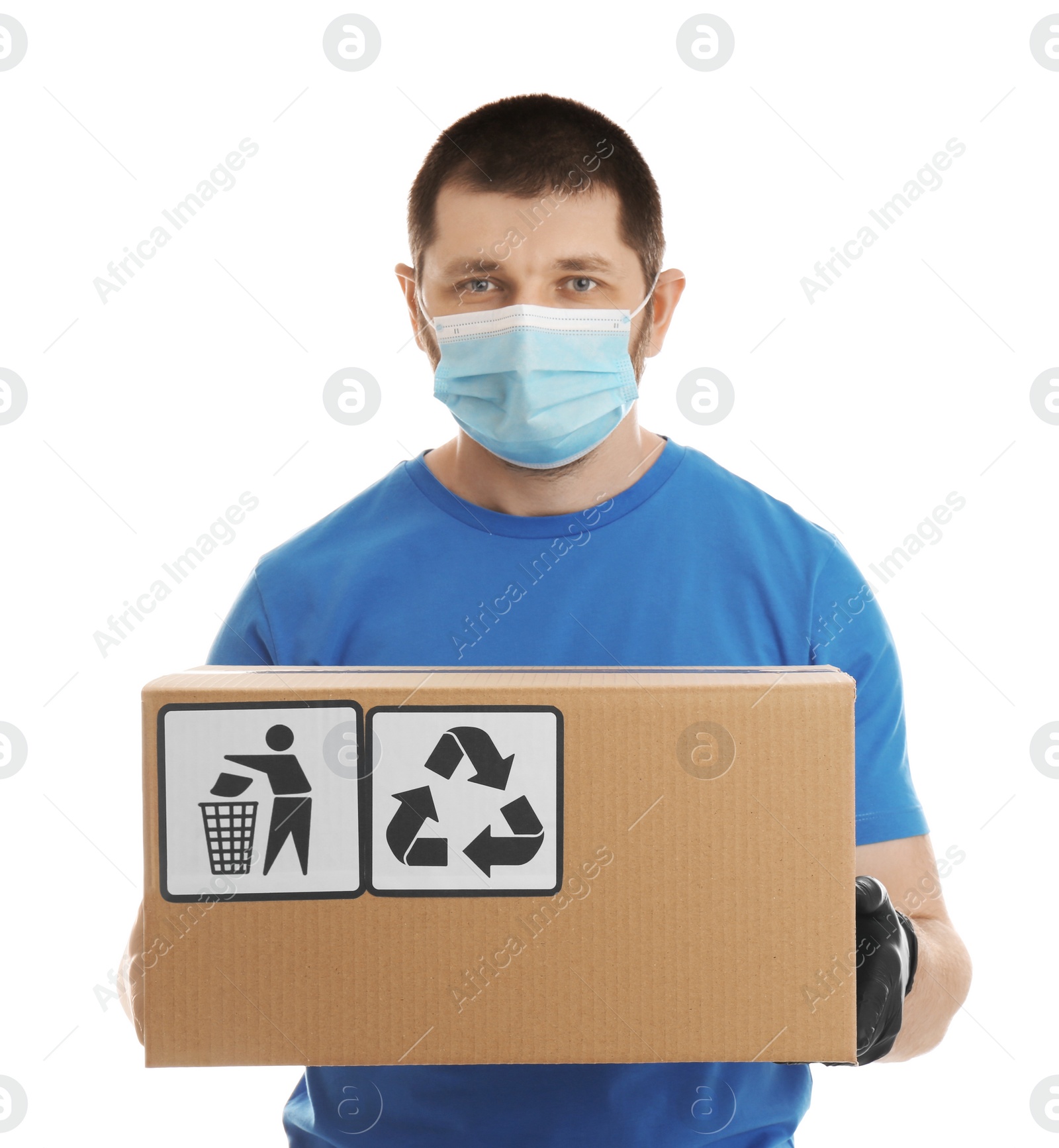 Photo of Courier in mask holding cardboard box with different packaging symbols on white background. Parcel delivery