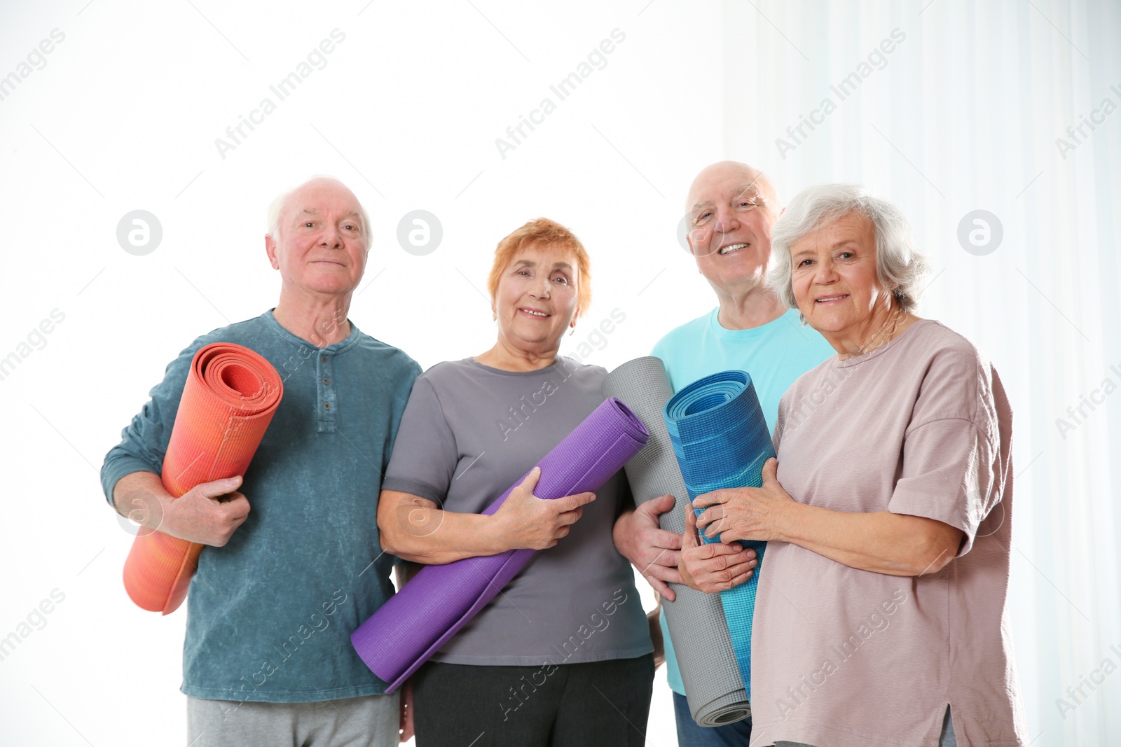 Photo of Elderly people with yoga mats on light background