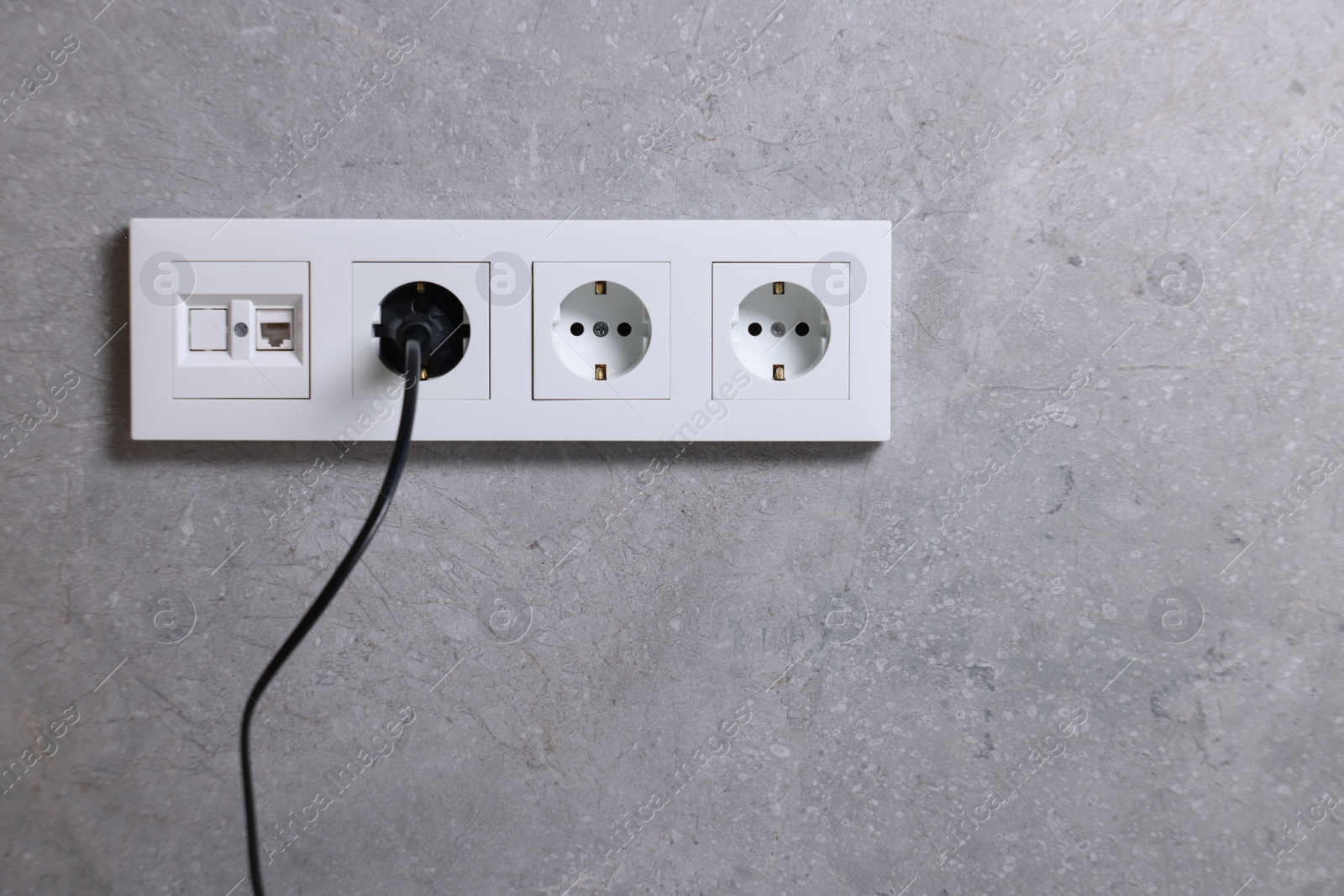 Photo of Power sockets and electric plug on grey wall, space for text