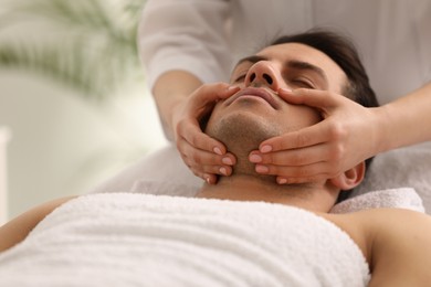 Photo of Man receiving facial massage in beauty salon