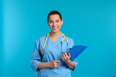 Portrait of young medical assistant with stethoscope and clipboard on color background