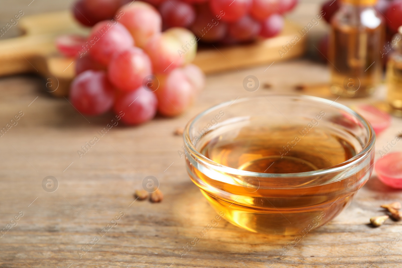 Photo of Natural grape seed oil and fresh berries on wooden table, space for text. Organic cosmetic