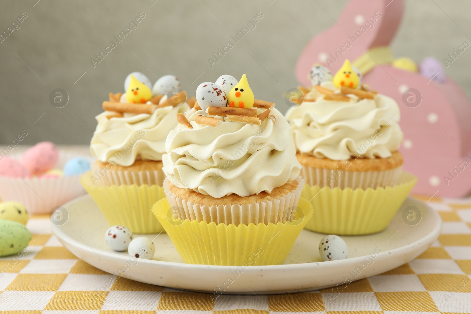 Photo of Tasty Easter cupcakes with vanilla cream on table, closeup