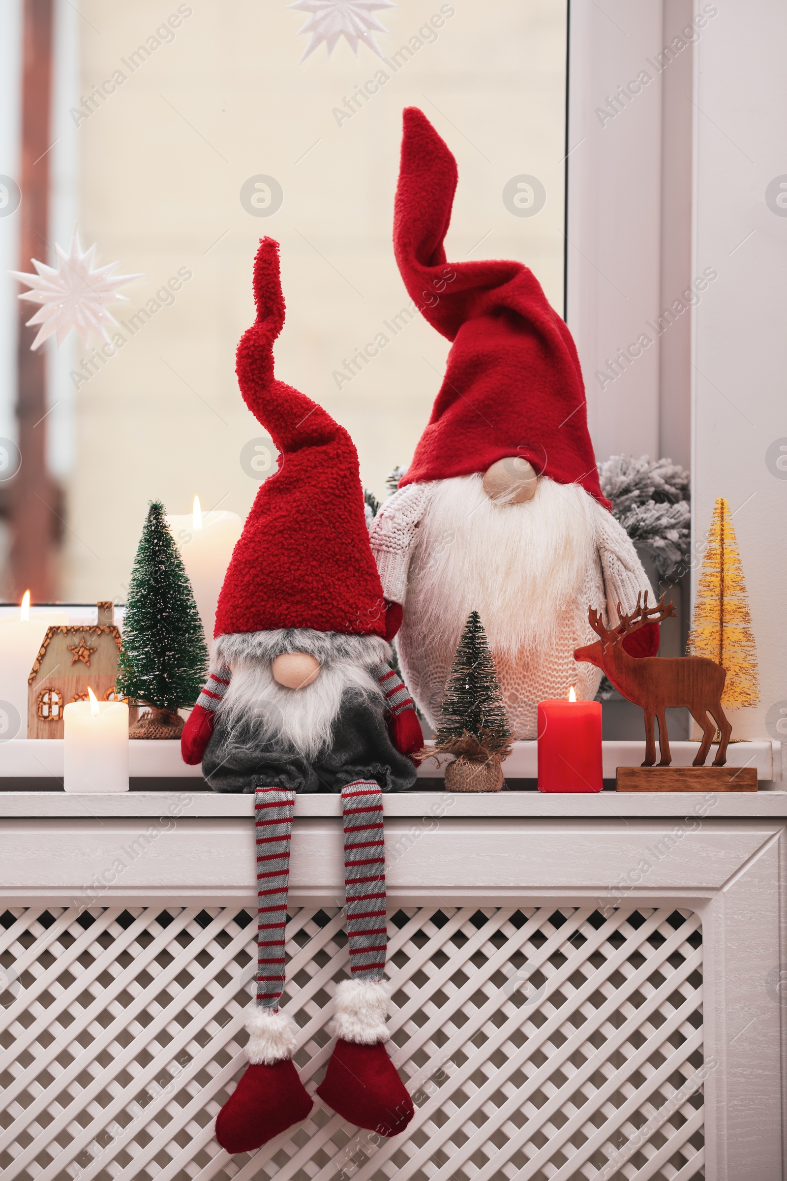 Photo of Cute Christmas gnomes and other festive decorations on windowsill in room