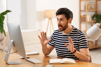 Home workplace. Emotional man having video conference at wooden desk in room