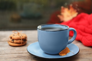 Cup of hot drink and cookies on window sill indoors. Cozy autumn atmosphere