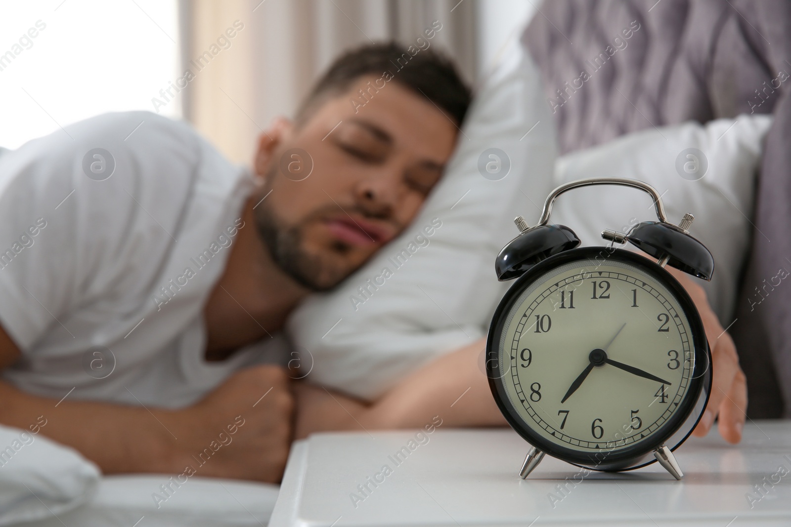 Photo of Man sleeping at home in morning, focus on alarm clock