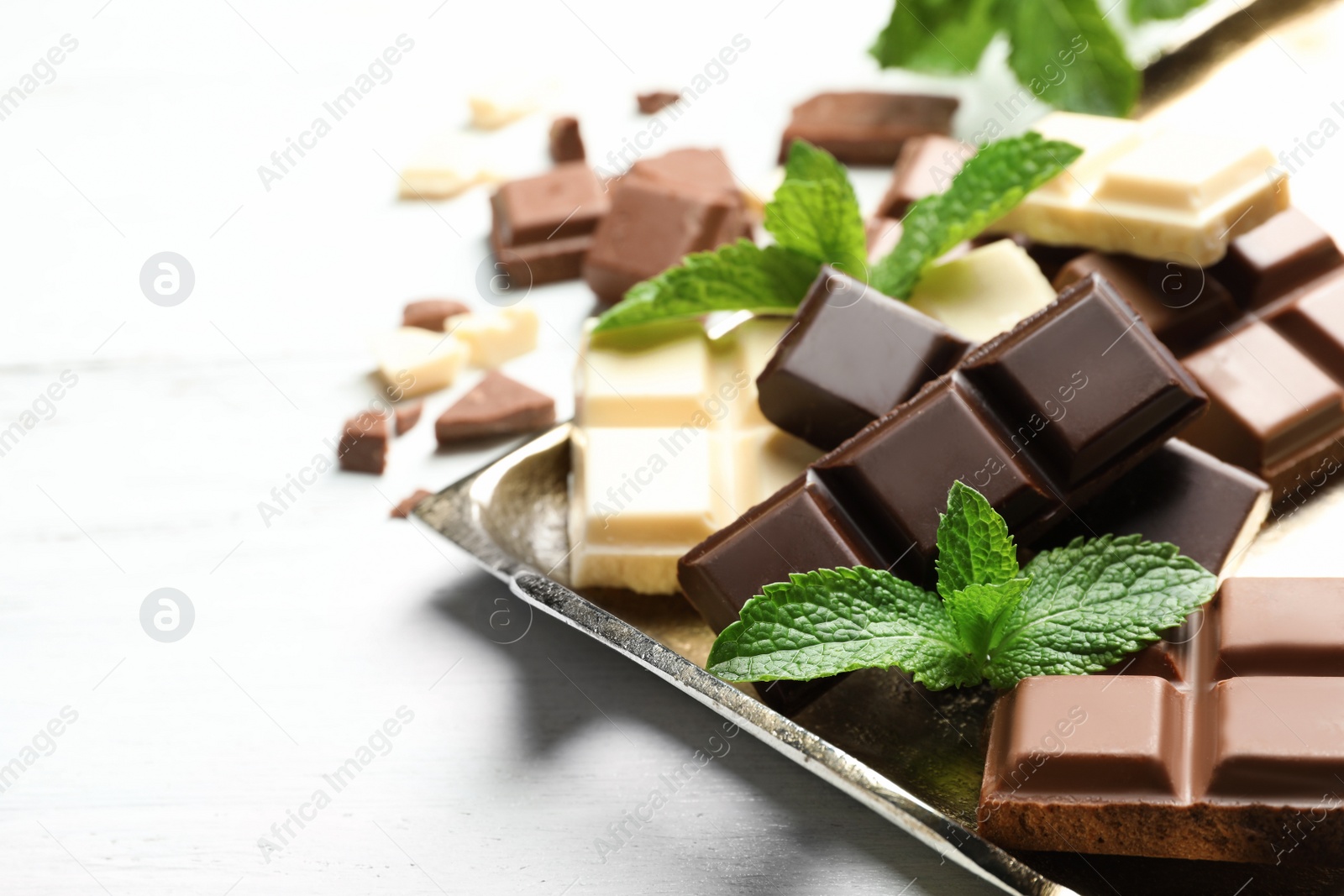 Photo of Different kinds of chocolate with mint on light table