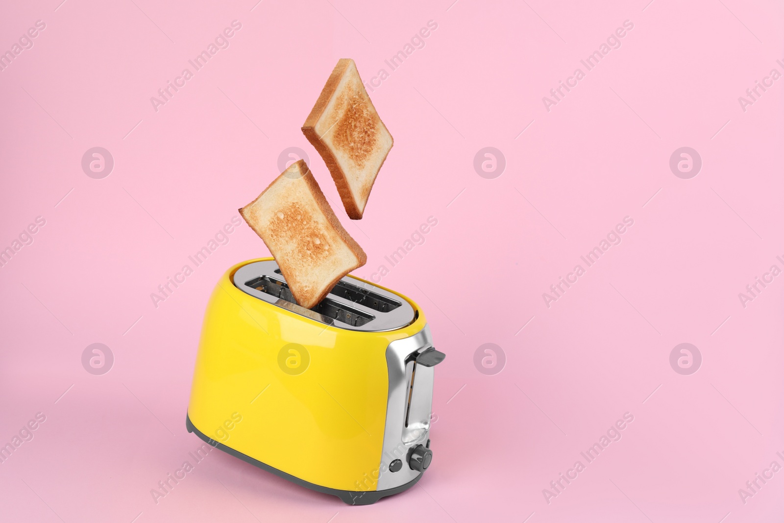 Photo of Bread slices popping up from modern toaster on pink background. Space for text