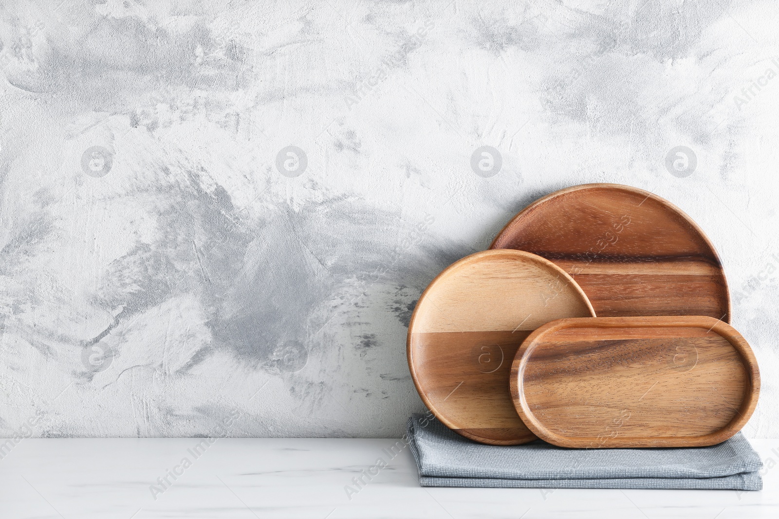 Photo of Set of wooden dishware on white marble table against textured wall. Space for text