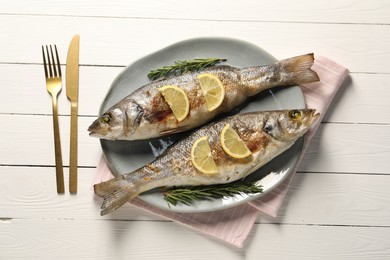 Photo of Delicious baked fish served on white wooden table, top view