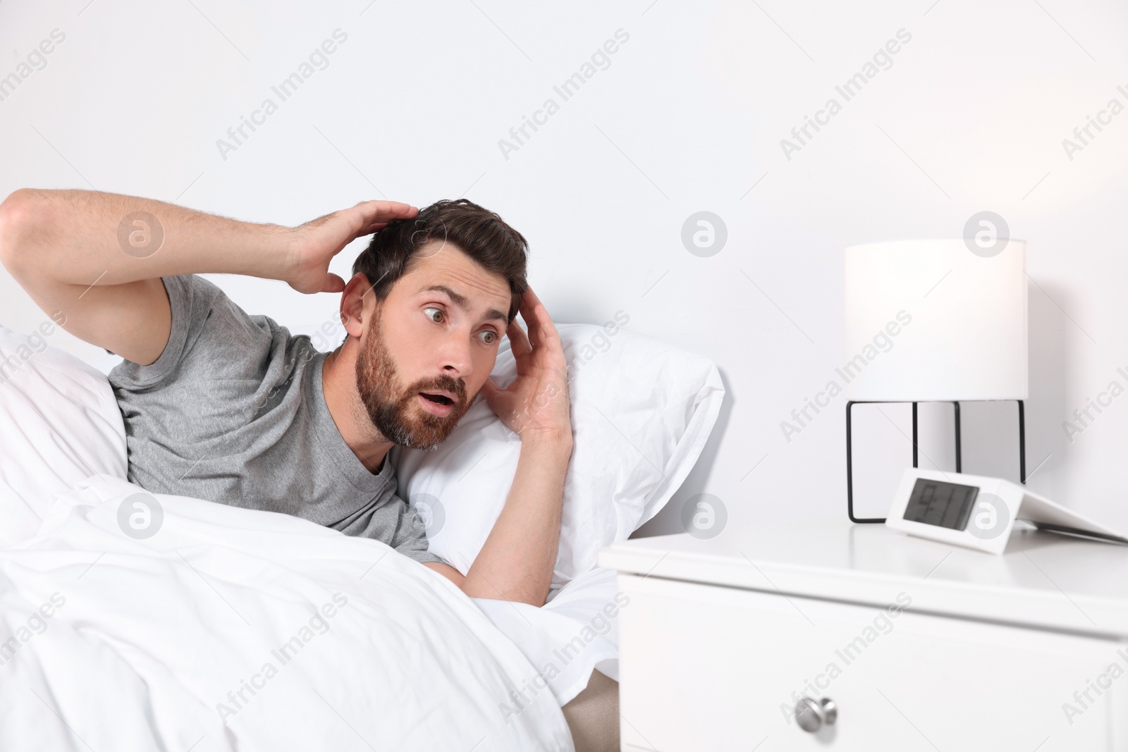 Photo of Emotional man in bed at home. Being late because of oversleeping