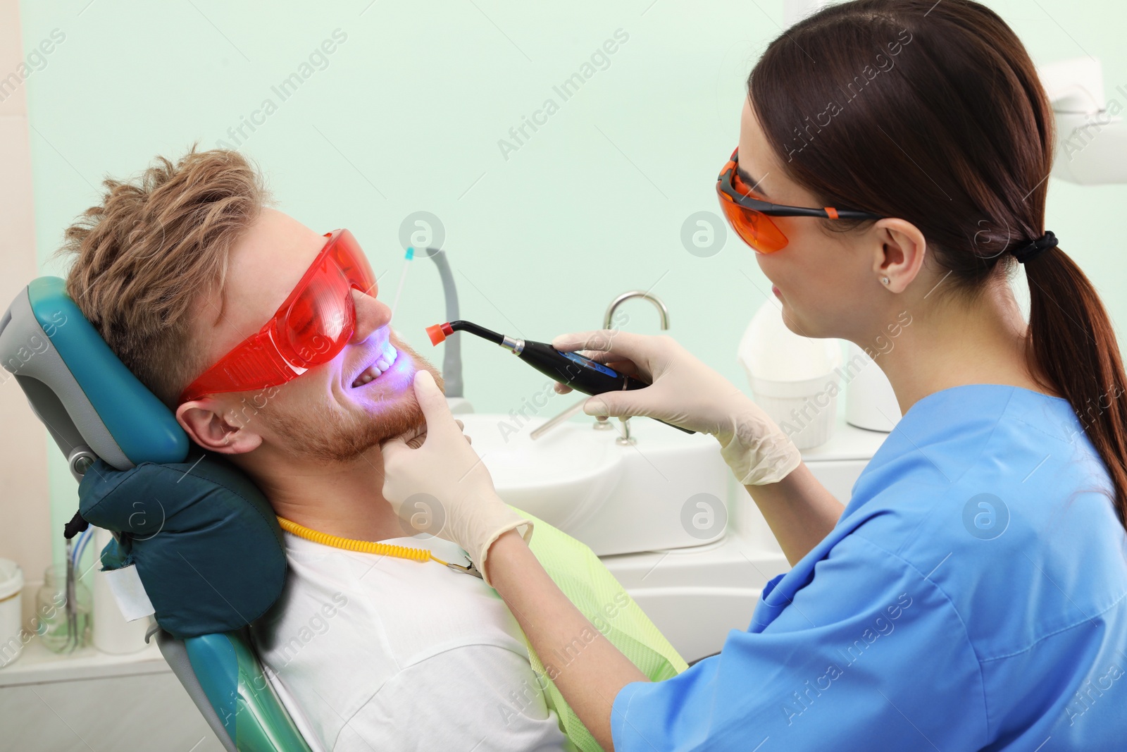 Photo of Professional dentist working with patient in modern clinic. Teeth whitening