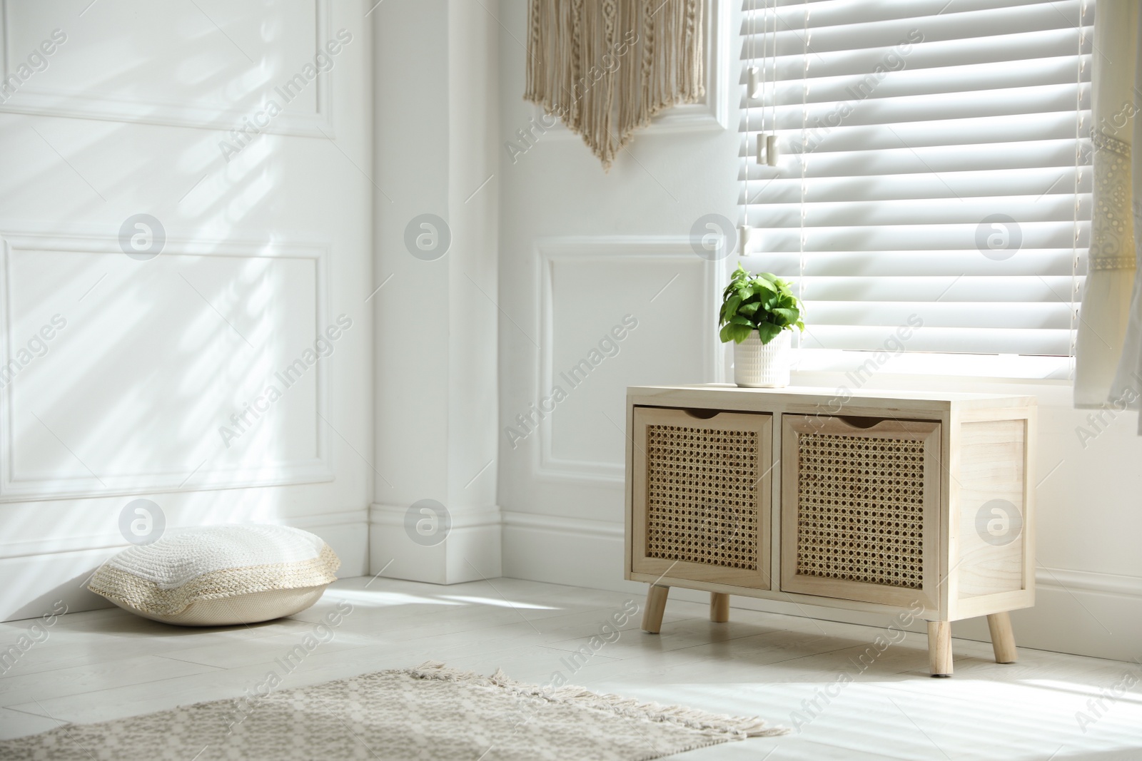 Photo of Wooden commode near window in room. Interior design