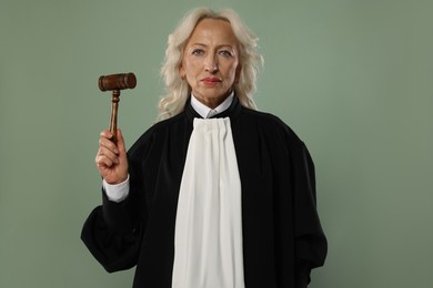 Photo of Senior judge with gavel on green background
