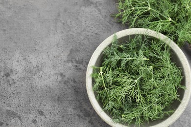 Bowl of fresh dill on grey table, flat lay. Space for text