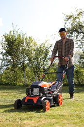 Man cutting green grass with lawn mower in garden