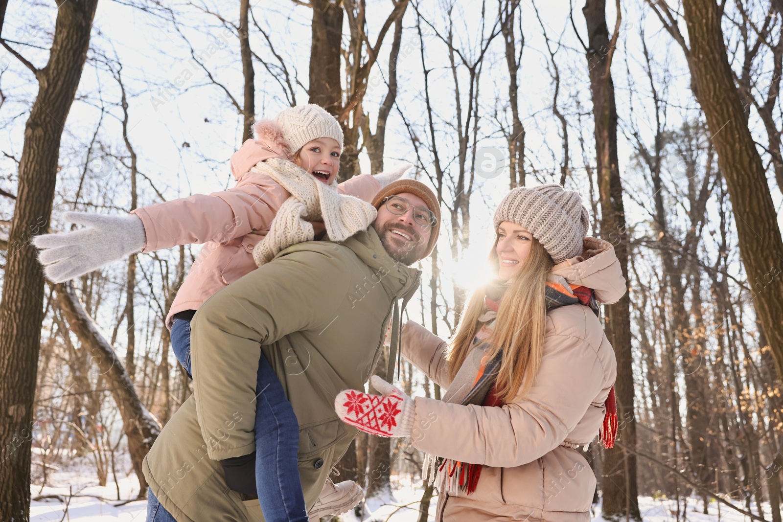 Photo of Happy family spending time together in sunny snowy forest