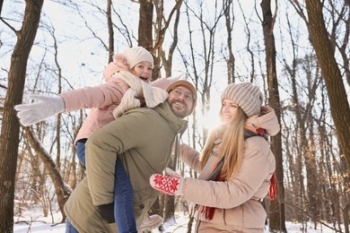 Happy family spending time together in sunny snowy forest