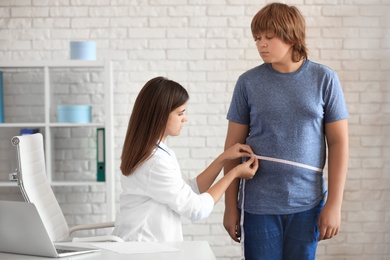 Photo of Female doctor measuring overweight boy in clinic