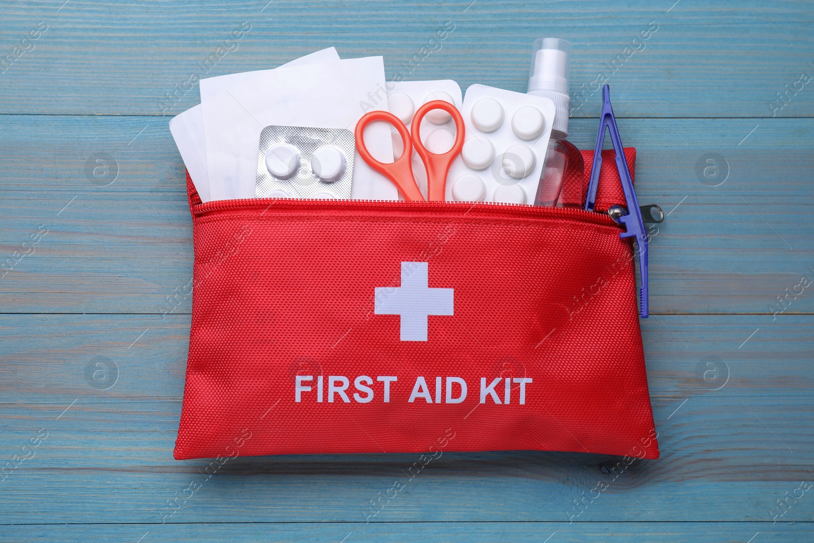 Photo of First aid kit on blue wooden table, top view