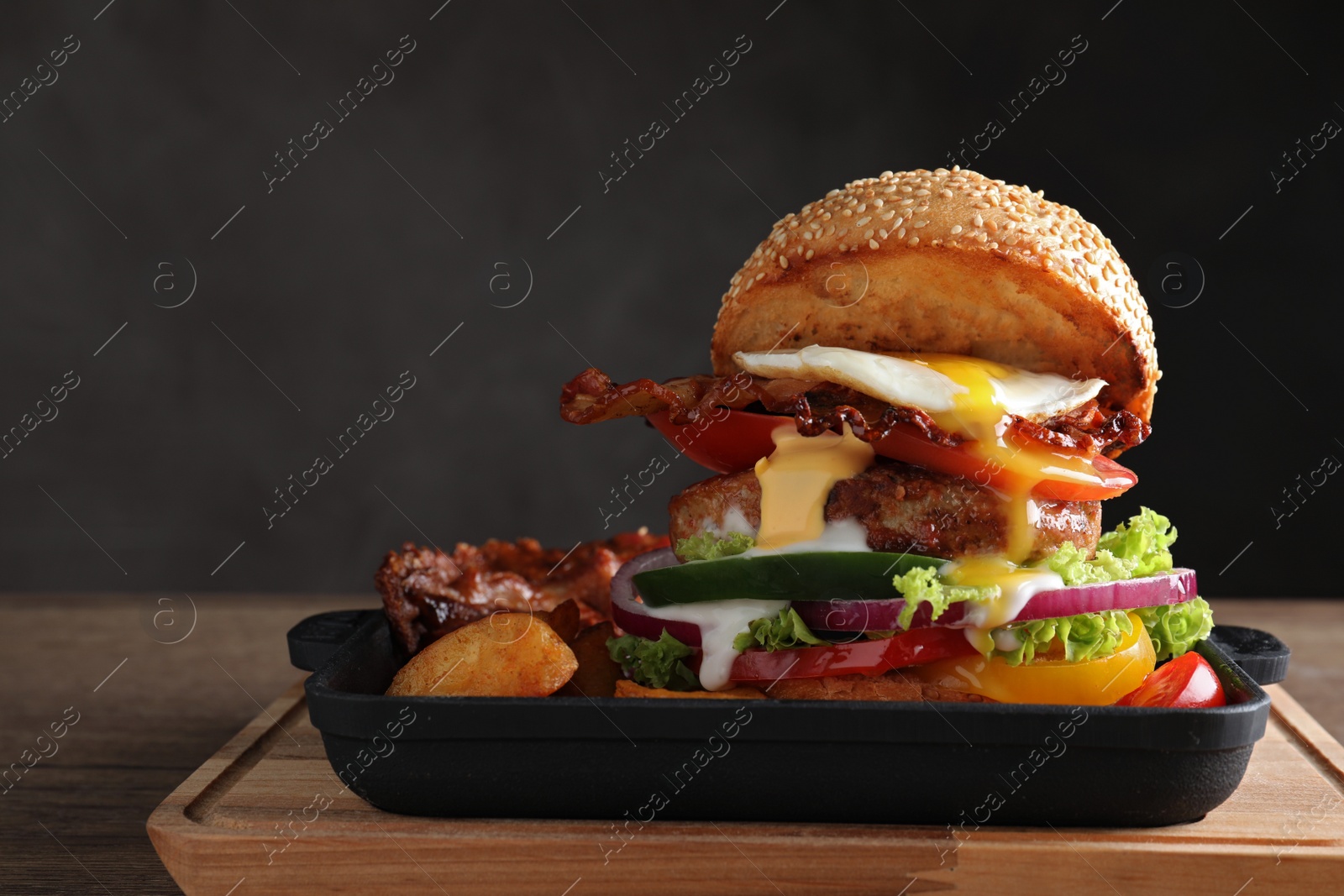 Photo of Serving pan with juicy bacon burger on wooden board. Space for text