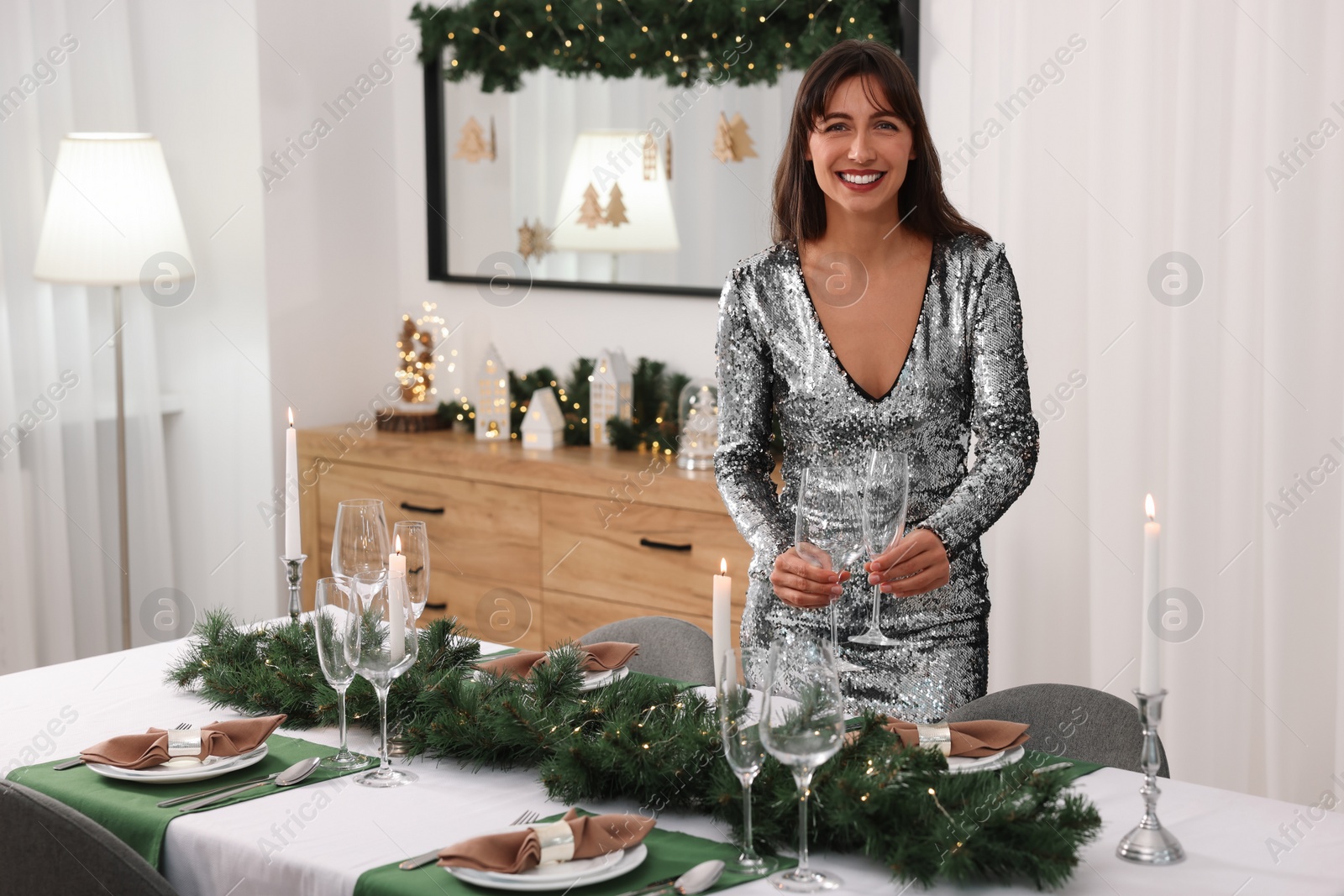 Photo of Smiling woman setting table for Christmas celebration at home. Space for text