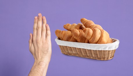 Gluten free diet. Man refusing from croissants on violet background, closeup