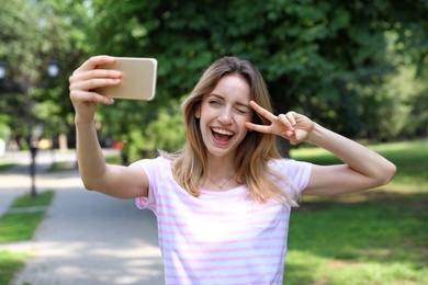 Happy young woman taking selfie in park