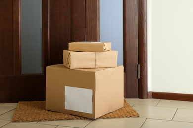 Photo of Parcels on rug near door. Delivery service