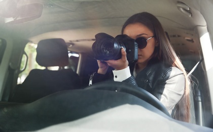 Private detective with camera spying from car