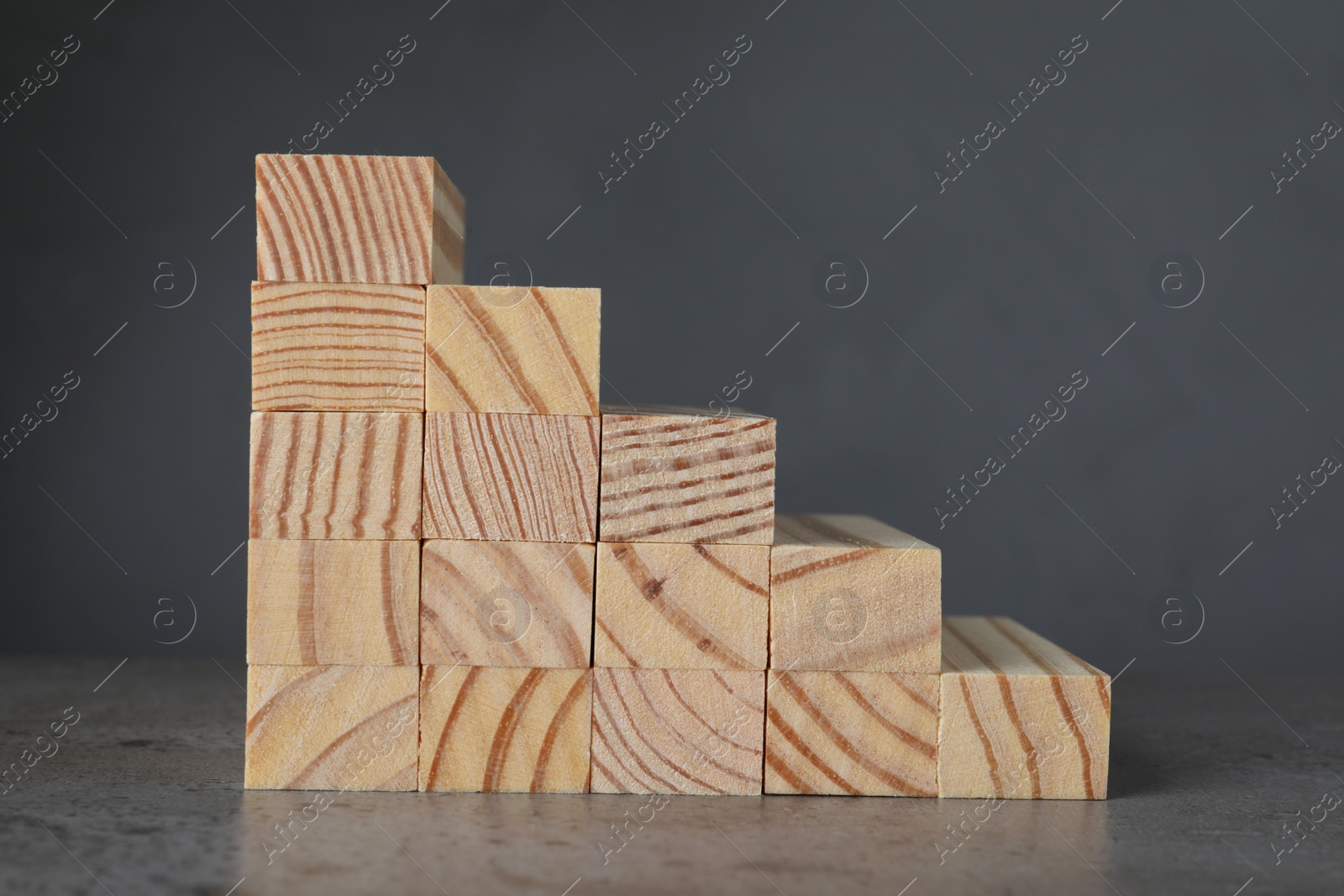 Photo of Steps made with wooden blocks on table against grey background. Career ladder