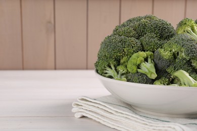 Photo of Bowl of fresh raw broccoli on white wooden table, closeup. Space for text