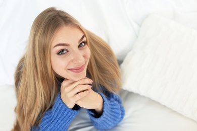 Photo of Beautiful smiling young woman lying in bed at home. Winter atmosphere