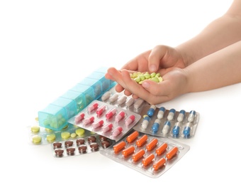 Photo of Little child with many different pills on white background, closeup. Danger of medicament intoxication